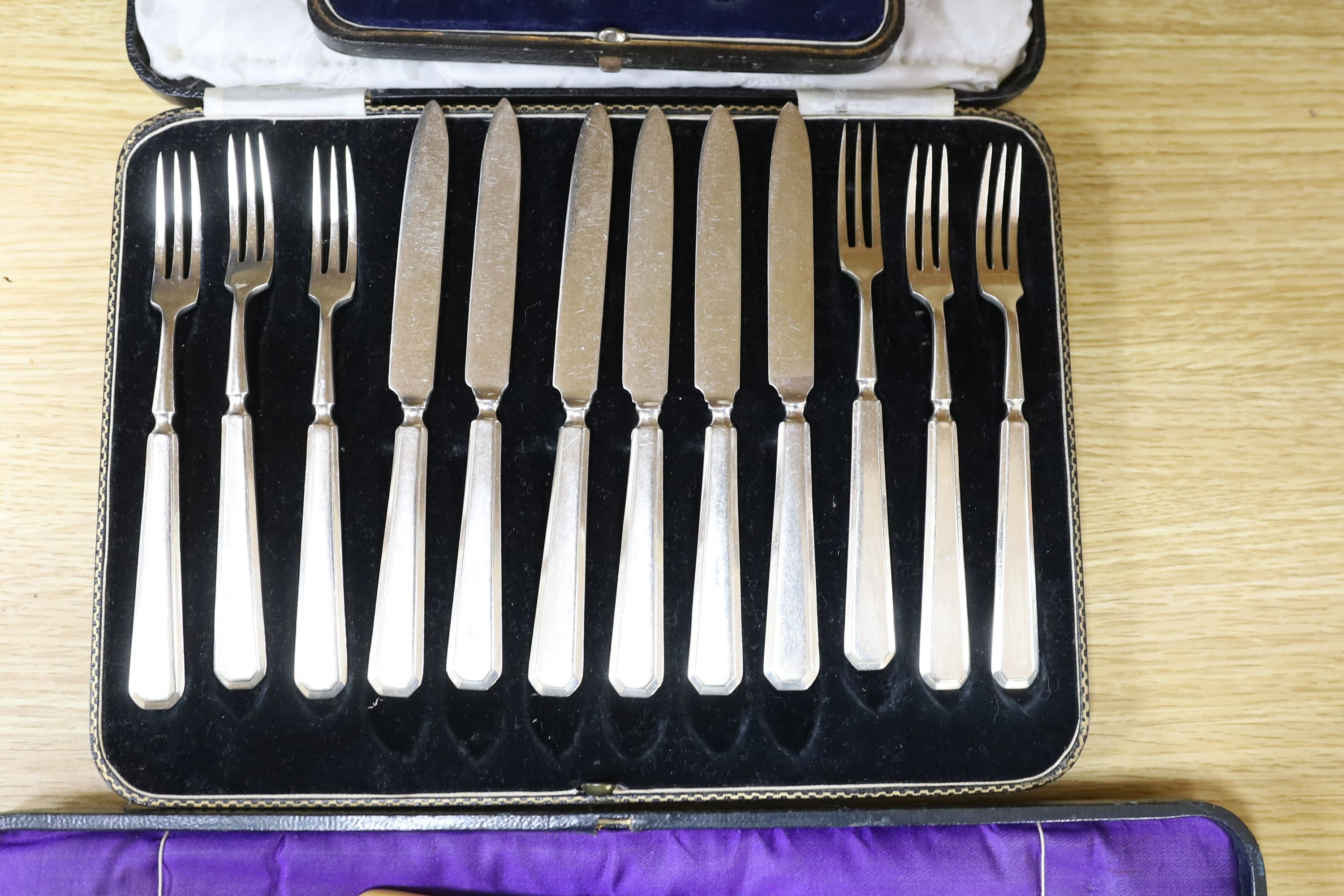 A cased pair of servers, and serving fork, cased silver coffee spoons, royal commemorative spoon, trefid coffee spoon, plated set of dessert knives and forks